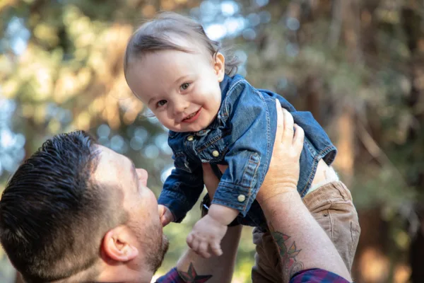 Parent holding child in the air outside
