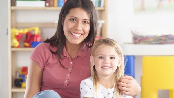 Child care teacher with her arm around a child.
