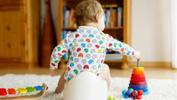 Toddler sitting on a potty while playing