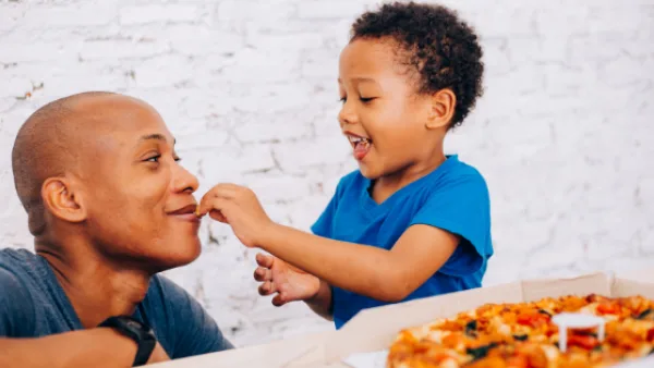 A child feeding a parent pizza