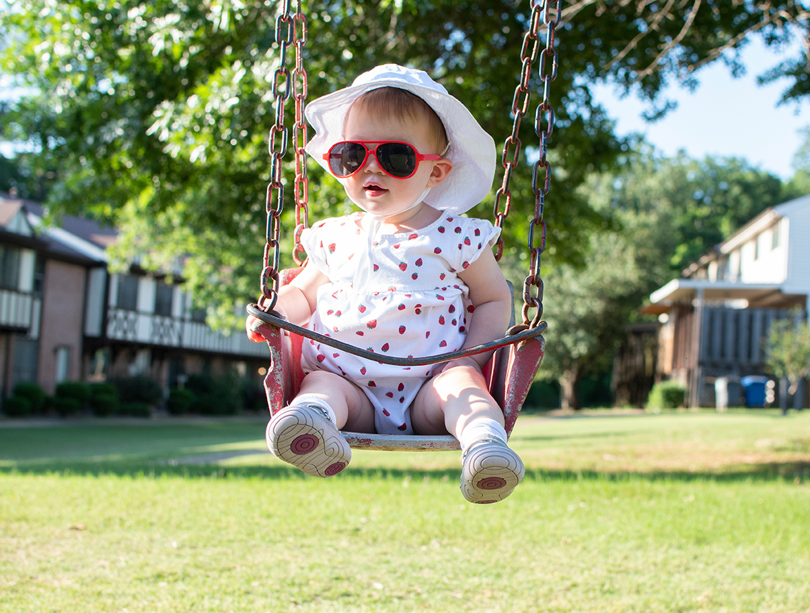 baby in hat and sunglasses swinging