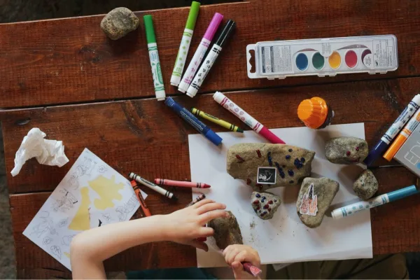 A picture of a child's hands using markers to color on rocks