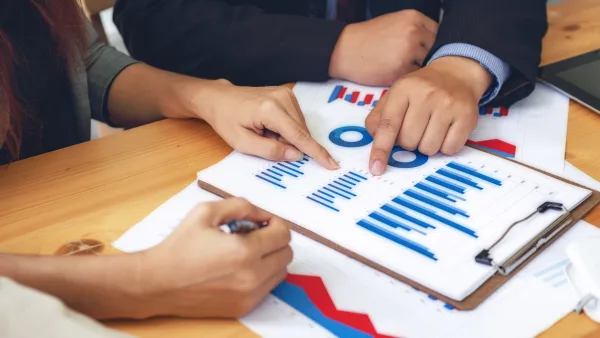 Hands of two individuals reading charts and graphs