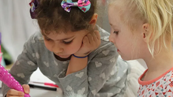 Girl writing while another girl watches